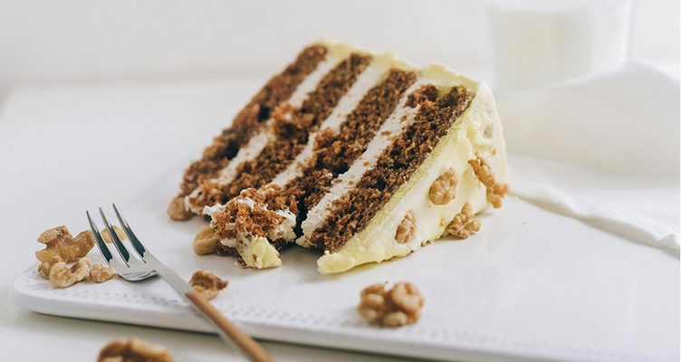 imagem de um bolo de cenoura americano com cobertura e recheio de creamcheese e nozes